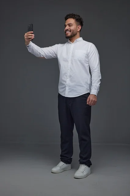 Smiling Saudi Man Taking Selfie with Smartphone in Studio