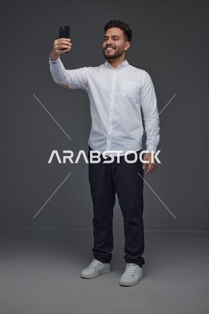 رجل سعودي يلتقط صورة سيلفي بالهاتف في الاستوديو