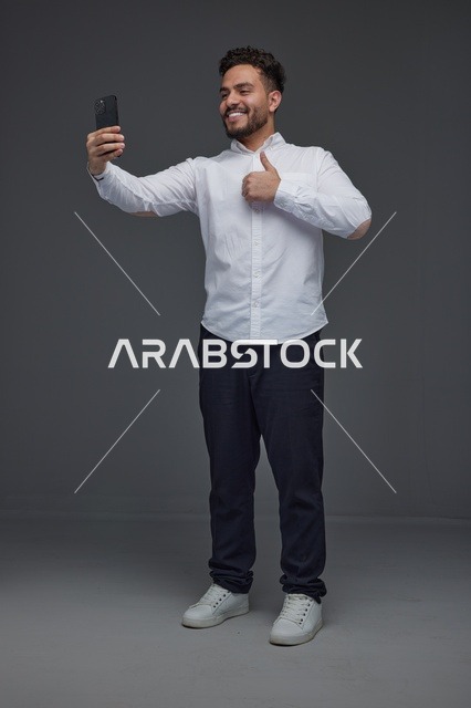 رجل سعودي يلتقط سيلفي بالهاتف الذكي مع علامة الإعجاب