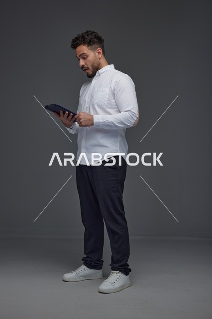 Saudi Man Using Digital Tablet on Gray Background