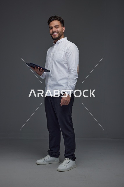 رجل سعودي يحمل جهاز لوحي في الاستوديو