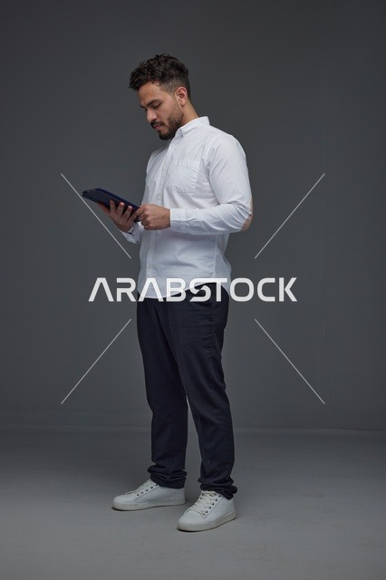 Saudi Man Using Tablet on Grey Studio Background