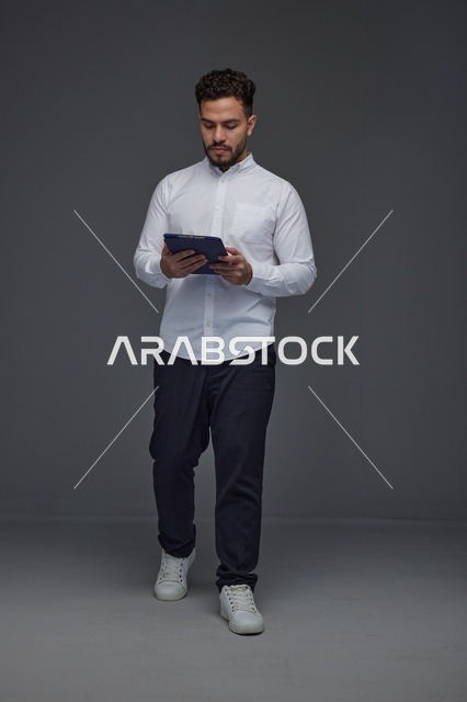 Saudi Man Using Digital Tablet in Gray Studio Background