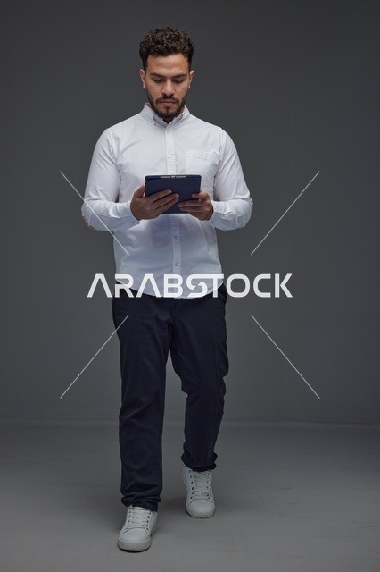 Saudi Man Using Digital Tablet in Studio Grey Background