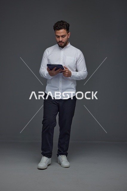 Saudi Man Using Digital Tablet in Grey Studio Background