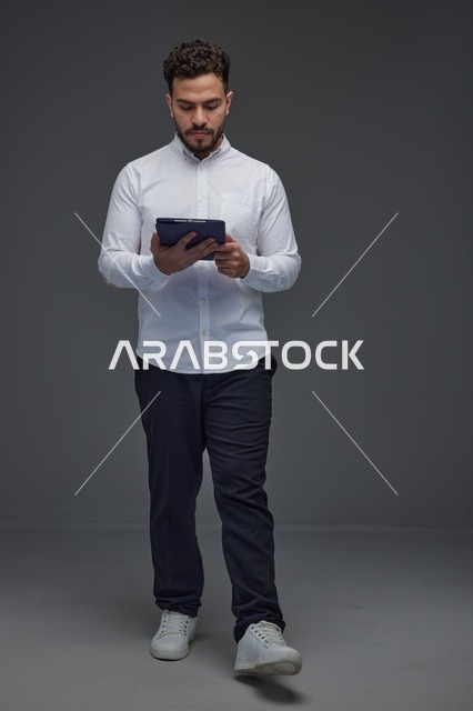 Saudi Man Using Digital Tablet on Grey Background