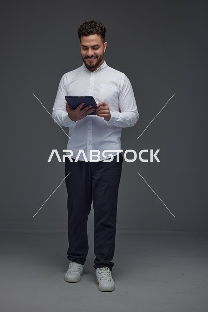 Saudi Man Using Digital Tablet Against Grey Background