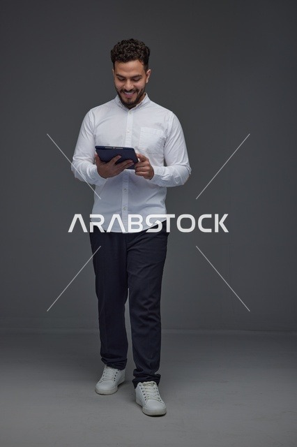 Saudi Man Using Digital Tablet on Grey Studio Background