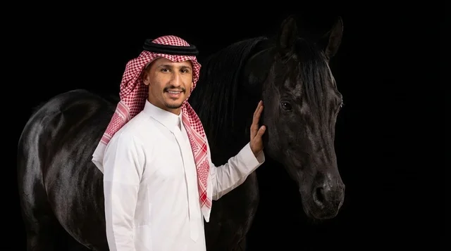 رجل سعودي باللباس التقليدي مع خيل عربي أسود في الاستوديو