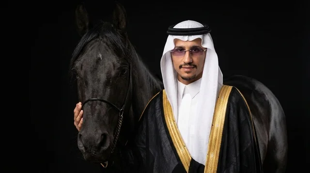 رجل سعودي مع خيل عربي أسود بالبشت التقليدي
