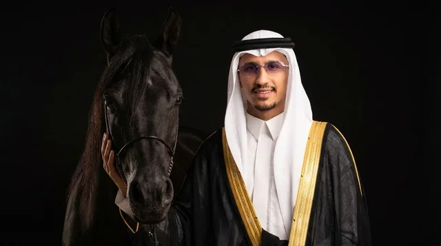 رجل سعودي مع خيل عربي أسود بالبشت التقليدي