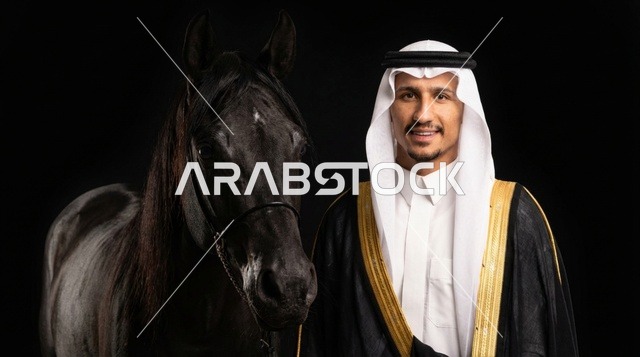 رجل سعودي مع خيل عربي أسود بالبشت والزي التقليدي