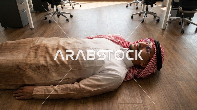 رجل عربي يرتدي الثوب يستلقي بداخل مكتب حديث