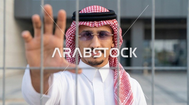 رجل سعودي خلف سياج سلكي يمد يده