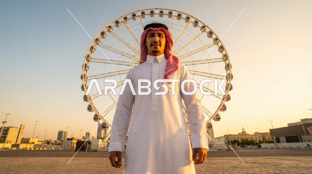 رجل سعودي أمام العجلة الدوارة وقت الغروب