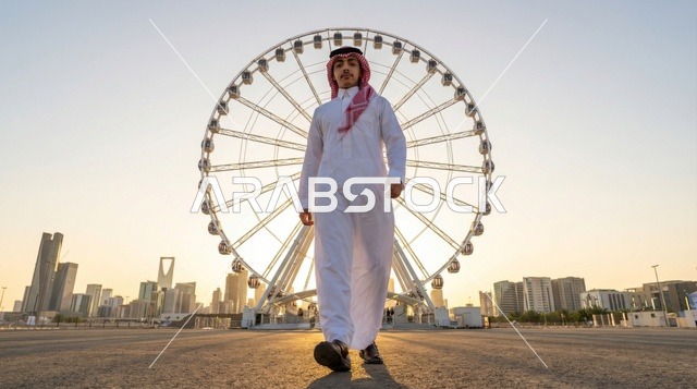 شاب سعودي في أفق الرياض أمام عجلة فيريس
