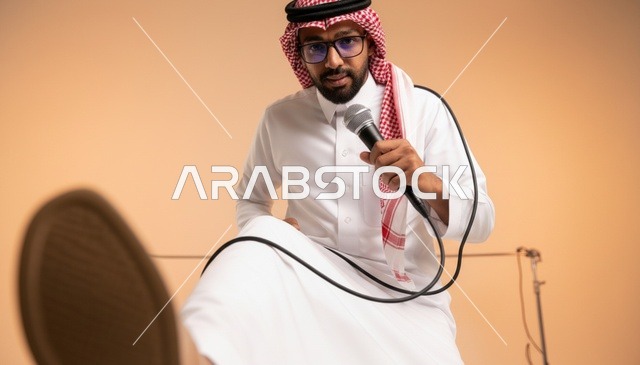 رجل سعودي يمسك بميكروفون بالزي التقليدي