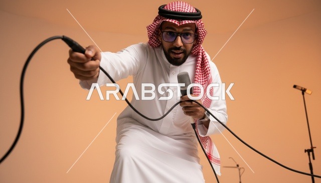 رجل سعودي بالزي التقليدي يمسك بميكروفون في الاستوديو