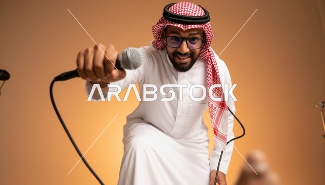 رجل سعودي بالثوب التقليدي يمسك ميكروفون في استوديو