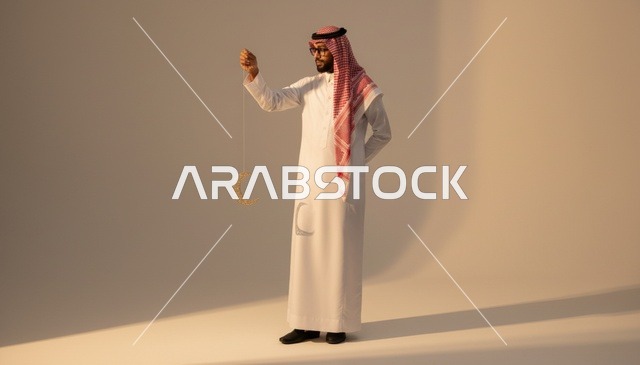 رجل سعودي يمسك بزينة الهلال في استوديو