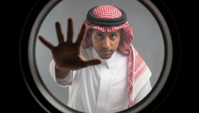 رجل سعودي يشير بالتوقف من فتحة الباب