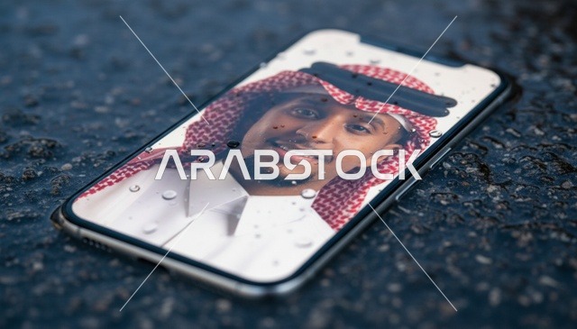 صورة رجل سعودي على شاشة هاتف فوق رصيف مبلل