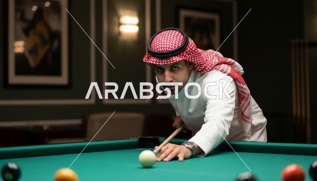 رجل سعودي بالزي التقليدي يلعب البلياردو في صالة ترفيه
