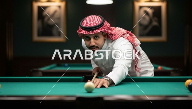 رجل سعودي يلعب البلياردو بالزي التقليدي