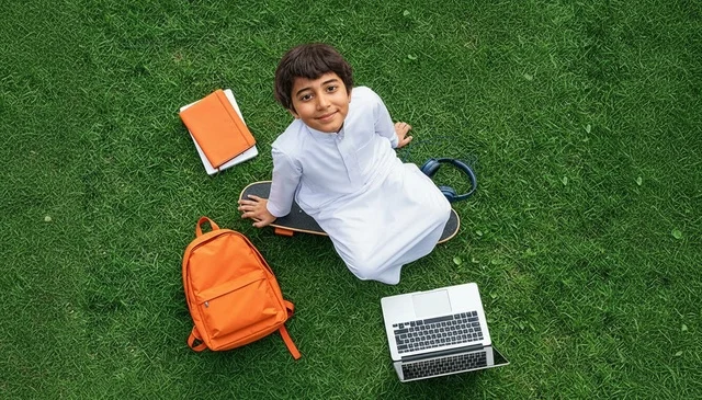 Saudi Boy in Traditional Thobe with Laptop on Green Grass