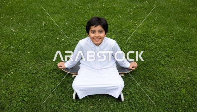 طفل سعودي بالثوب التقليدي يجلس على لوح تزلج