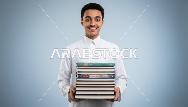 طالب سعودي بالثوب الأبيض يحمل مجموعة من الكتب