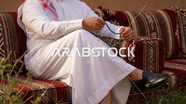 رجل سعودي بالثوب التقليدي والمسبحة في جلسة عربية