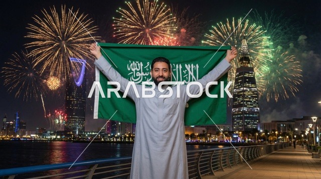 رجل سعودي يحمل العلم في الرياض مع ألعاب نارية ليلاً