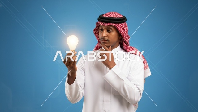 رجل سعودي يمسك بمصباح مضيء للتعبير عن الابتكار