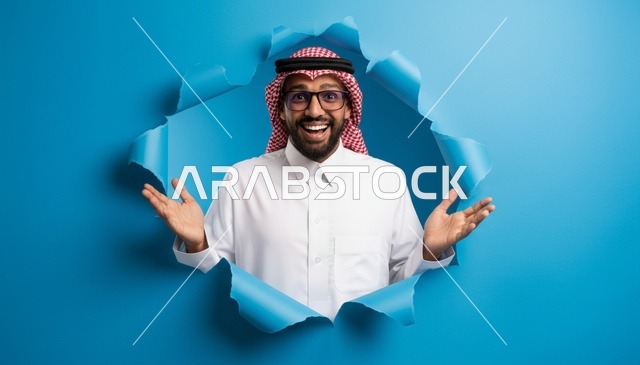 رجل سعودي يطل من خلال خلفية زرقاء مبتسماً
