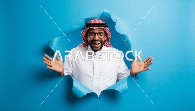 رجل سعودي متحمس يظهر من خلال ورق أزرق ممزق