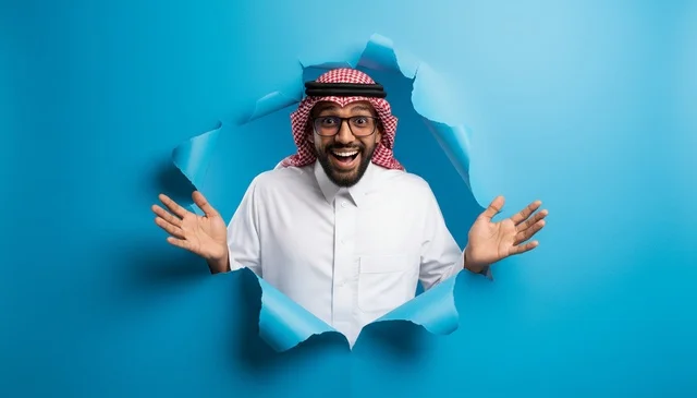 Excited Saudi Man Emerging Through Torn Blue Paper