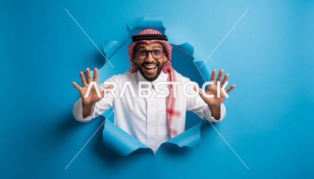 رجل سعودي متحمس ينظر من خلال ورق أزرق ممزق