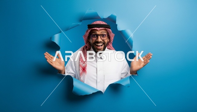رجل سعودي يظهر بحماس من خلف ورق ممزق أزرق