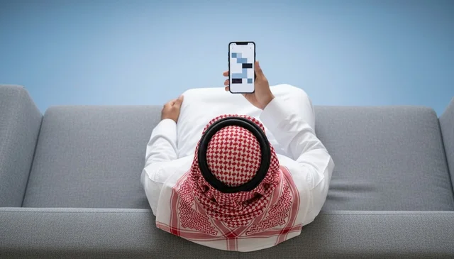 Saudi Man Using Smartphone on Sofa Top View