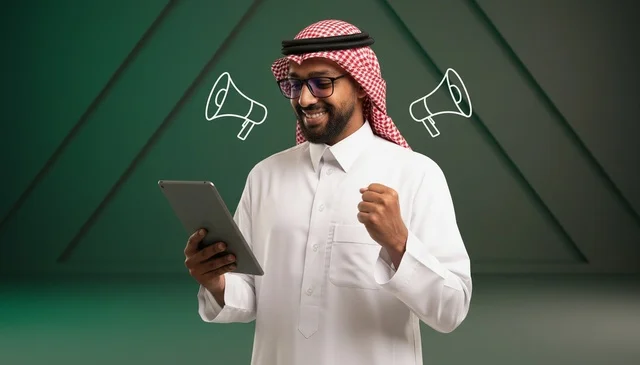 رجل سعودي يحمل تابلت يحتفل بنجاح حملة تسويقية