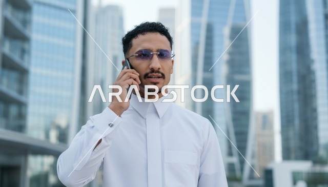 Arab Man in White Thobe Using Smartphone in City