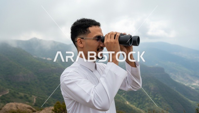 رجل سعودي يستخدم المنظار في الجبال الضبابية