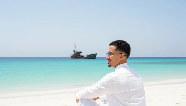 رجل سعودي على الشاطئ مع إطلالة سفينة محطمة