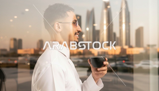 رجل سعودي بالثوب يشرب القهوة أمام أفق مدينة الرياض