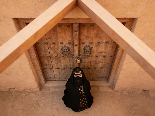 امرأة سعودية بالزي التقليدي أمام مبنى تراثي قديم