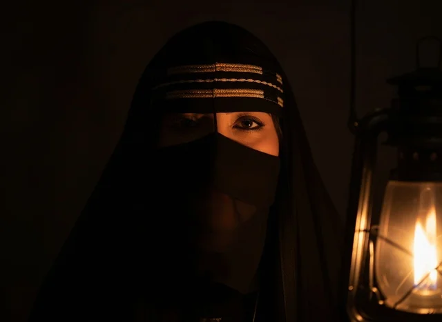 امرأة سعودية بالنقاب التقليدي تحمل فانوساً مضيئاً