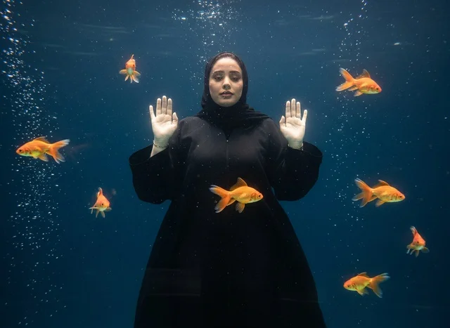 Saudi Woman in Abaya Underwater with Goldfish