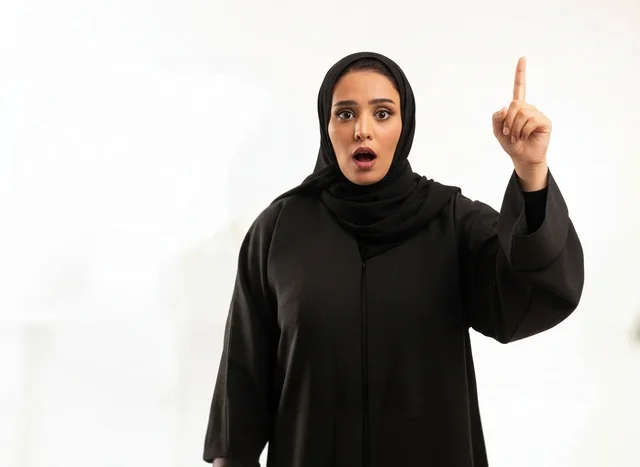 Emirati Woman in Black Abaya Pointing Upward Studio Shot