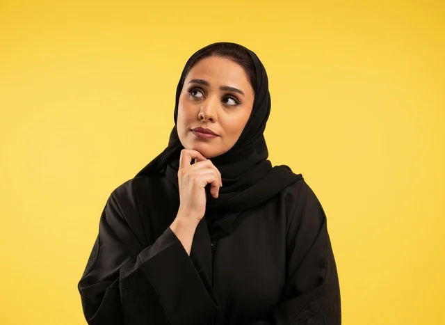 Pensive Saudi Woman in Black Abaya on Yellow Background